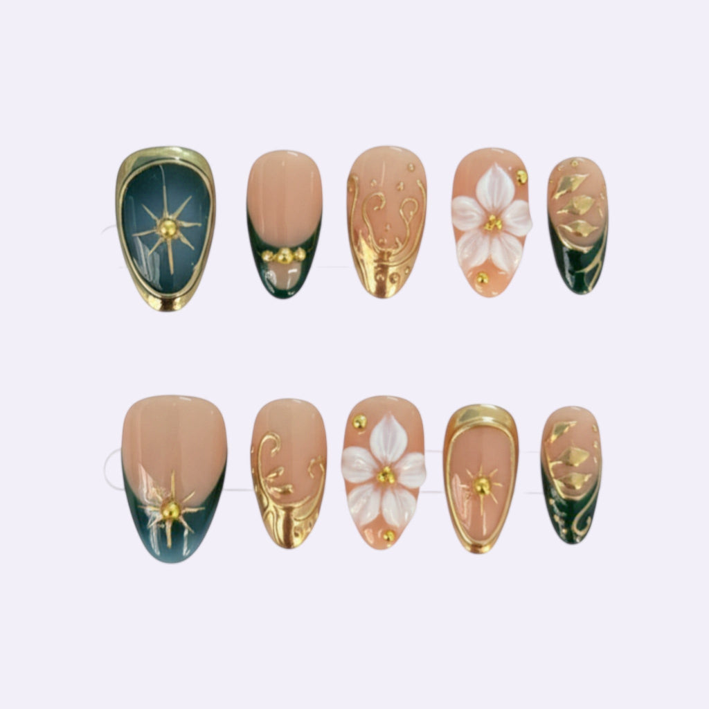 PearlFizzy Emerald Whisper press-on nails with nude base, emerald green tips, gold detailing, 3D flowers, and sun motifs.